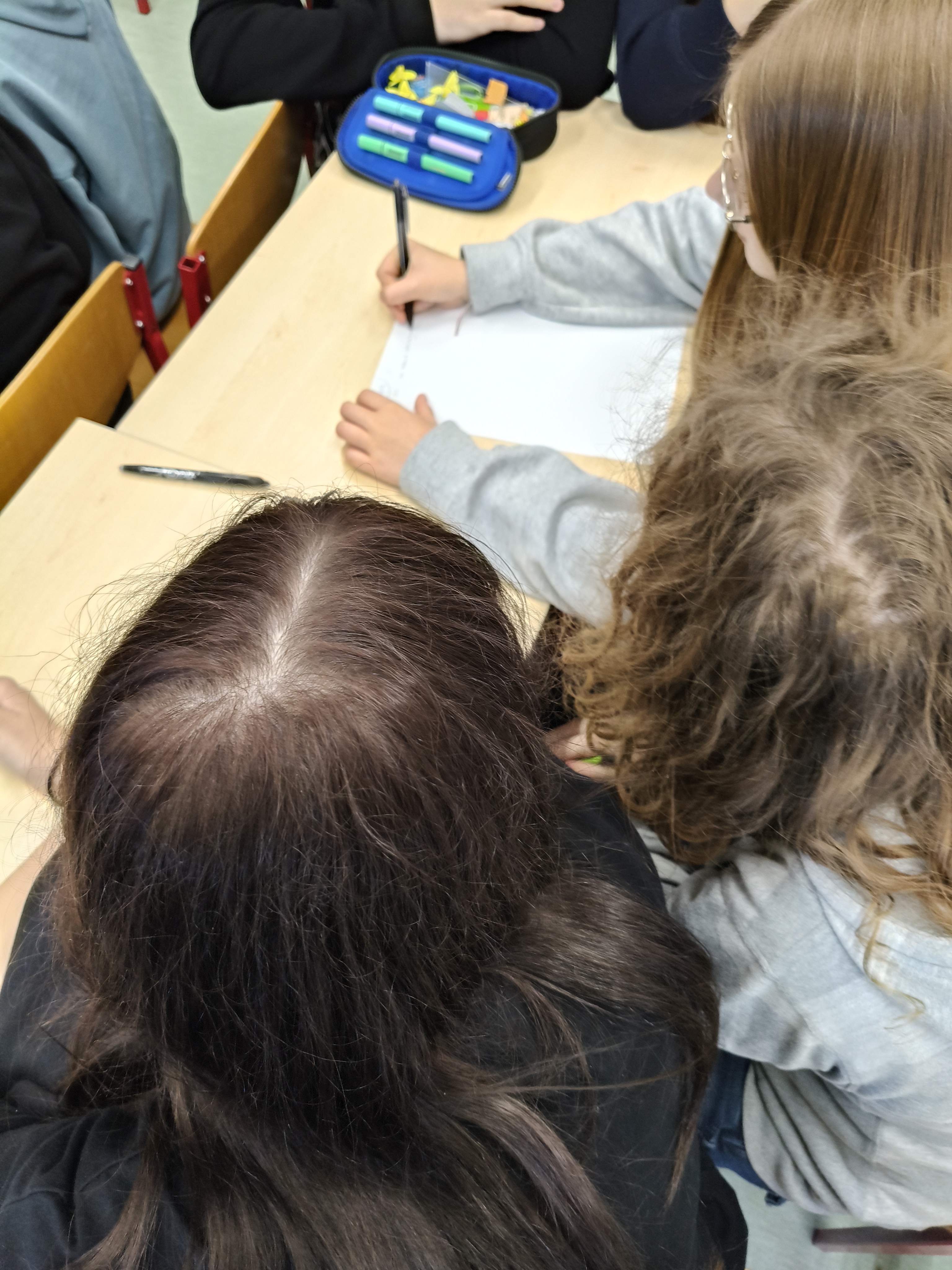 Zdjęcie prezentuje młodzież pracującą w grupach nad zadaniem  